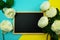 Blackboard and bunch of peony flower on blue and yellow background flat lay