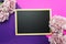 Blackboard and bunch of peony flower on pink and purple background flat lay