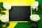 Blackboard and bunch of peony flower on yellow and green background flat lay