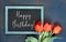 Blackboard and bunch of red tulips on abstract dark background, text