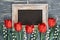 Blackboard and bunch of red tulips and lily of the valley flowers on rustic background, space