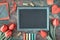 Blackboard framed with red tulips, wooden heart, color chalks an