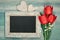 Blackboard framed with red tulips and wooden hearts on neutral b