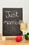 A blackboard with just married on it displayed with a glass of champagne and a red rose