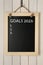 Blackboard with phrase GOALS 2023 and empty checklist on hanging on white wooden background