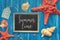 Blackboard with Summer time chalk text, with sea shells, rope and star fish on blue  wood