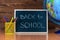 A blackboard with text Back to School, a set of colored pencils with a glass and a globe on a wooden background. Concept