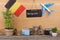 blackboard with text & x22;Belgium& x22;, flag of the Belgium, airplane model, little bicycle and suitcase, camera, compass