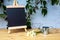 Blackboard on wooden table with daisies and miniature watering can