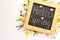 Blackboard with words HELLO SPRING and fresh flowers on white background, flat lay