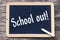 On a blackboard is written with chalk: School out