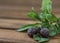 Blackcurrant berries in hoarfrost, fresh mint leaves on a dark wooden table. Ingredients for smoothies. Close-up. Horizontal frame