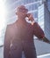 A blackman in a suit speaking on smartphone.