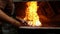 Blacksmith heating metal rod in fire