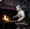 Blacksmith heats item before forging. focused on the fire