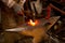 The blacksmith manually forging the molten metal on the anvil in smithy.