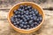 Blackthorn berries in clay bowl on wood background