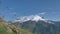 Blades of grass slowly sway against the background of the giant snow-white Mount Elbrus, the highest point in Europe