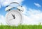 Blank alarm clock on grass with sky, copy space