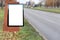 Blank billboard on city asphalt road on a clean day with lot of trees