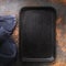 Blank black cast iron tray and napkin on the table, top view. Food background