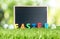 Blank blackboard with colorful easter word and paint eggs on green grass field at outdoor garden bokeh light background. Happy ea