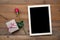 Blank blackboard, gift box and red rose on wood background