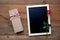 Blank blackboard, gift box and red rose on wood background