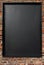 Blank blackboard menu sign on a red brick wall.