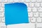 Blank blue sticky note on a profile gray computer keyboard