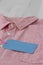 Blank blue tag label on a mens pink shirt with white buttons.