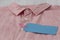 Blank blue tag label on a mens pink shirt with white buttons.