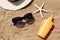 Blank bottle of sunscreen, starfish and beach accessories on sand, above view