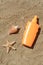 Blank bottle of sunscreen, starfish and seashell on sand, flat lay