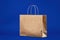 Blank brown paper carrier bag with handles for shopping. Paper bag on a blue background, responsible attitude to the environment.