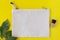 Blank canvas makeup bag on a bright yellow background with green leaves