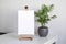 Blank canvas mockup on wooden easel and green houseplant on white table