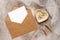 Blank card mockup in brown envelope, ribbon, ears of wheat and jewelry. Feminine wedding invitation template. Top view, flat lay