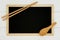 Blank chalkboard with wooden spoon and chopstick on white wood plank background.