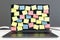 Blank colored sticker notes on laptop screen on light office table at grey wall background