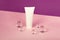 Blank cosmetics tube on the pink and purple isometric background.Glass balls around it.Cleanliness and purity concept