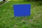 Blank dark blue sign on a green grass lawn on metal stand