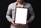 A blank diploma or a mockup certificate in the hand of a man employee wearing shirt on black background. The vertical picture