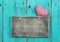 Blank distressed wood sign with red checkered heart hanging on rustic antique teal blue door