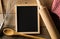 Blank, empty, black chalkboard with wooden rolling pin, wire whisk and red checkered dish towel flat lay from above on brown