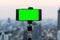 Blank empty green screen mobile smartphone taking a photo or video live on a tripod with blurry city background in social