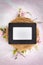 Blank empty white sign in a black wooden picture frame laying on a bird next with pink and white spring flowers flat lay