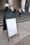 Blank empty white sign board on concrete floor in front of entrance way steps of building outdoor