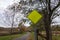 Blank fluorescent green triangular yield sign near a country walking path near trees