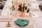 Blank green envelopes with stamps lie on a transparent plate on a set table. A lighted candle is burning on the left